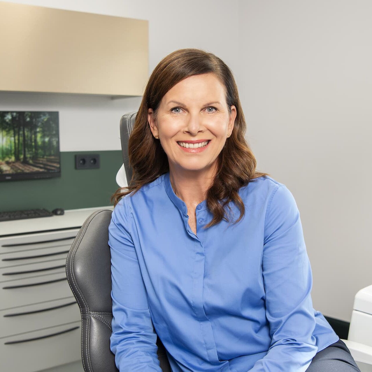 Patientin lächelt auf dem Behandlungsstuhl