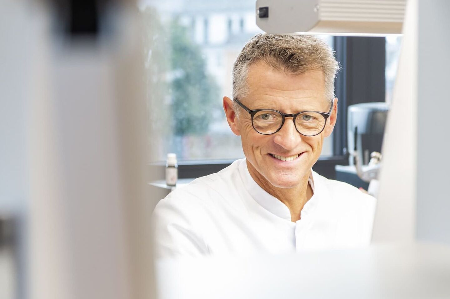 Zahntechniker sitzt im Dentallabor und lächelt